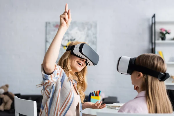 Concentration sélective de la femme positive dans le casque vr ayant idée près de l'enfant à la maison — Photo de stock