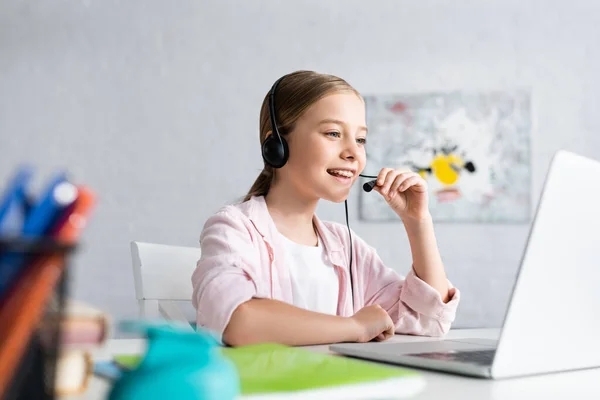 Enfoque selectivo del niño sonriente usando auriculares durante la educación en línea - foto de stock