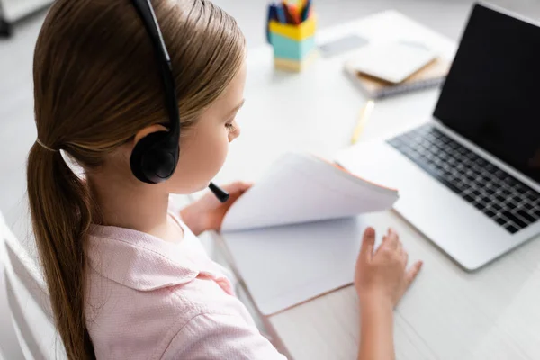 Focus selettivo del bambino in cuffia che tiene copia del libro durante l'apprendimento elettronico — Foto stock