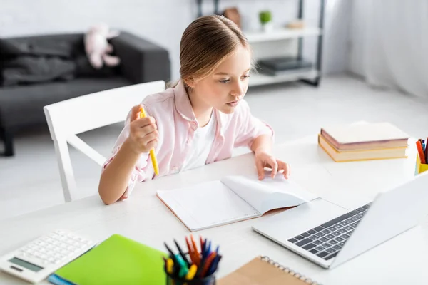 Concentration sélective de l'enfant mignon regardant l'ordinateur portable pendant l'éducation électronique à la maison — Photo de stock