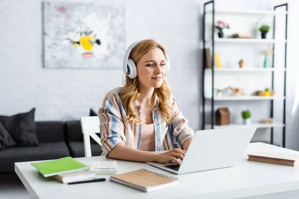 Selective focus of pretty woman working with laptop and headphones — Stock Photo