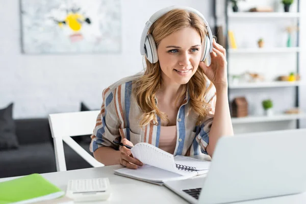 Selektiver Fokus attraktiver Frauen mit Kopfhörern, die während des Online-Studiums auf den Laptop schauen — Stockfoto