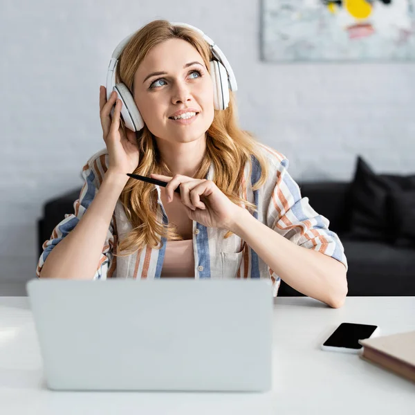 Focus sélectif de belle pigiste adulte travaillant avec ordinateur portable et écouteurs — Photo de stock