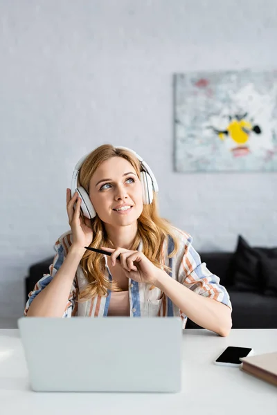 Enfoque selectivo del freelancer adulto que sostiene la pluma y trabaja con el ordenador portátil - foto de stock