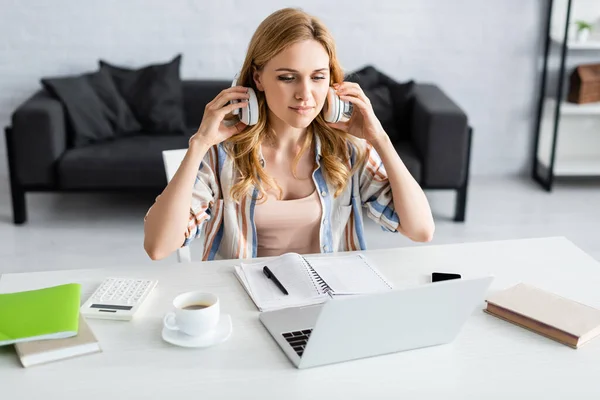Selective focus of attractive freelancer working with laptop and headphones — Stock Photo