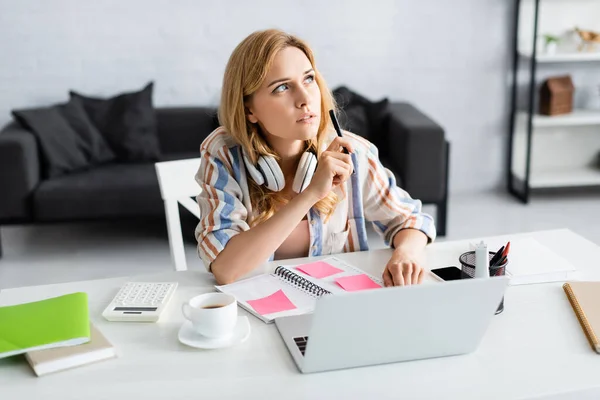 Selective focus of pensive woman working with laptop and notes — Stock Photo