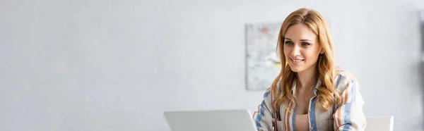 Foto panorámica de la mujer sonriente usando el ordenador portátil - foto de stock