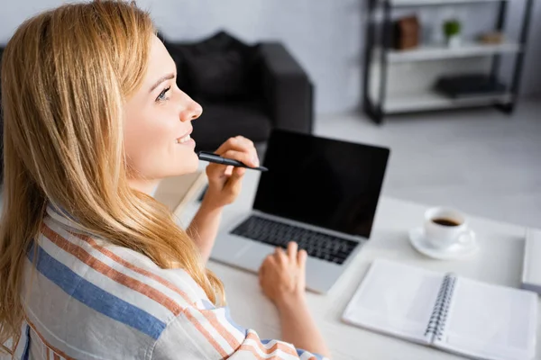 Selective focus of woman smiling while working with laptop — Stock Photo