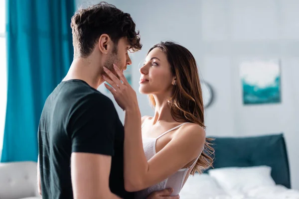 Beautiful woman touching cheek of handsome boyfriend in bedroom — Stock Photo