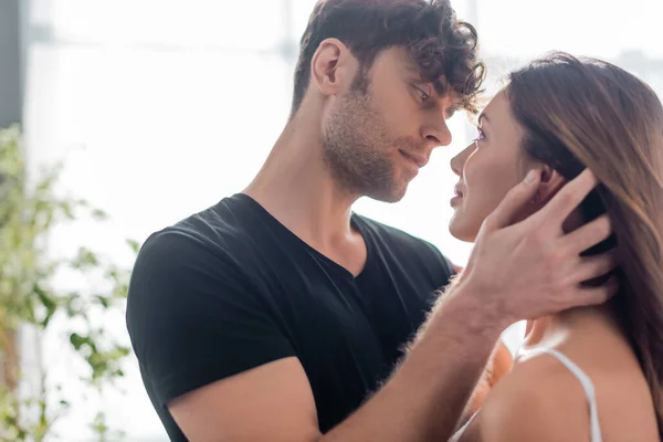 Selective focus of handsome man touching and looking at attractive woman at home — Stock Photo