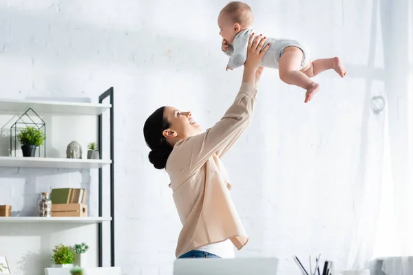 Feliz mãe segurando nos braços bonito bebê filho no bebê romper — Fotografia de Stock