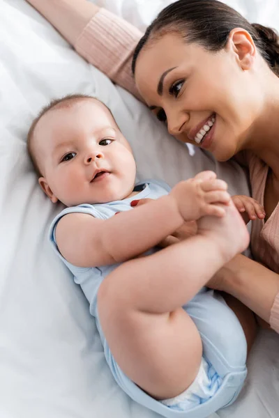 Overhead view of mother looking at infant baby while lying on bed — Stock Photo