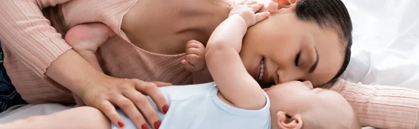 Horizontal crop of mother with closed eyes lying on bed with baby boy — Stock Photo