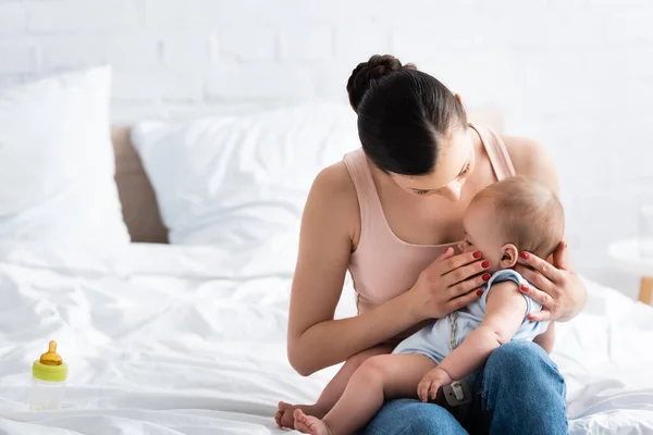 Mother touching cute baby son with bare feet in bedroom — Stock Photo