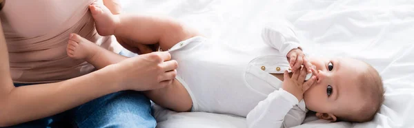 Horizontal image of mother wearing baby romper on infant boy with pacifier — Stock Photo