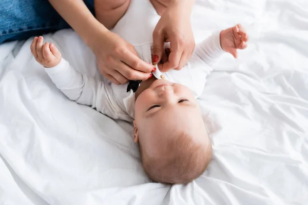 Overhead view of mother wearing baby romper on son — Stock Photo