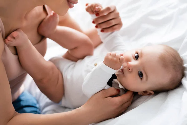 Весела мати тримає руки босоніж немовляти — стокове фото
