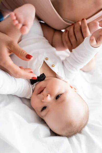 Selective focus of mother touching bare feet of cute infant son on bed — Stock Photo