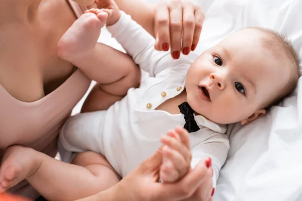 Selective focus of mother touching barefoot infant son on bed — Stock Photo