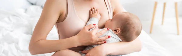 Panoramic crop of caring mother breastfeeding baby boy in bedroom — Stock Photo