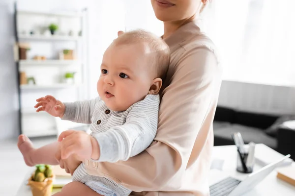 Mãe segurando em braços adorável bebê filho em casa — Fotografia de Stock