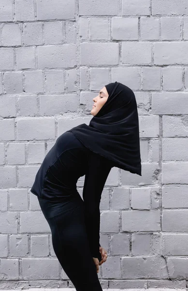 Profilo di sportiva musulmana che esercita vicino al muro di mattoni — Foto stock