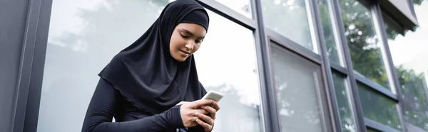 Encabezado del sitio web de la joven mujer musulmana utilizando el teléfono inteligente - foto de stock