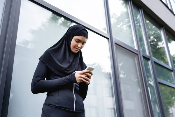 Visão de baixo ângulo da jovem mulher muçulmana usando smartphone — Fotografia de Stock