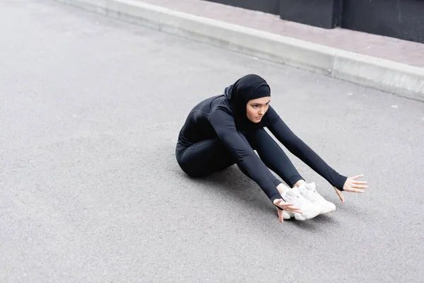 Arabian woman in hijab exercising on asphalt — Stock Photo