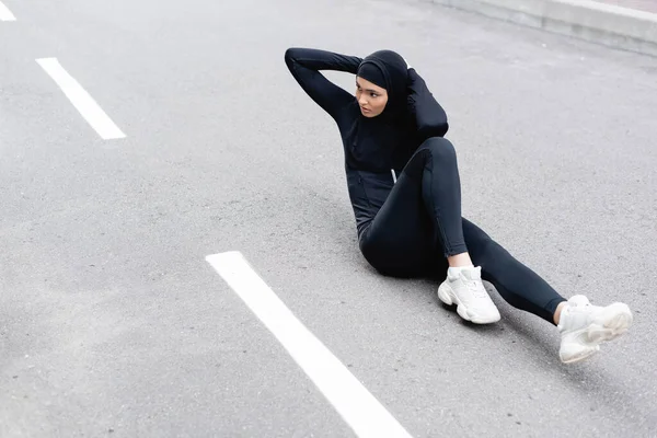 Arabe sportive en hijab faisant de l'exercice sur asphalte — Photo de stock