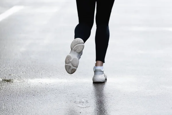 Vista ritagliata di sportiva in scarpe da ginnastica in esecuzione fuori — Foto stock