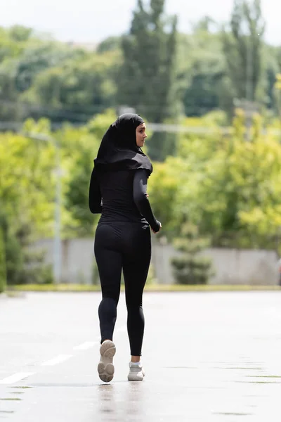 Joven deportista árabe en hijab y ropa deportiva corriendo afuera - foto de stock