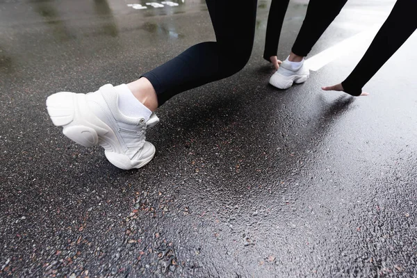 Обрізаний вид жінки в білих кросівках, що стоять на стартовій позі зовні — стокове фото