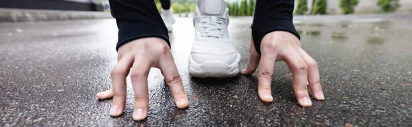 Coltura orizzontale di corridore in scarpe da ginnastica bianche in piedi in posa di partenza all'esterno — Foto stock