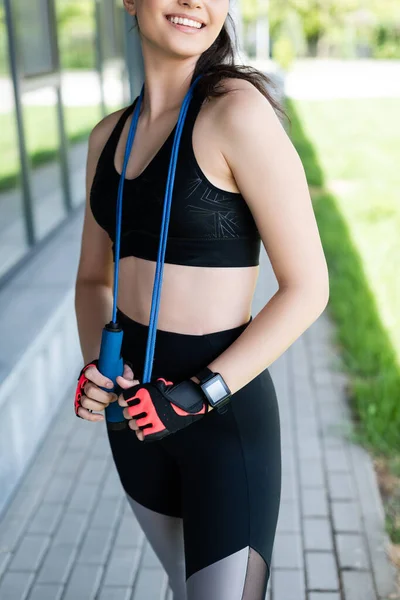 Обрезанный вид счастливой женщины в спортивных перчатках держа скакалку — стоковое фото