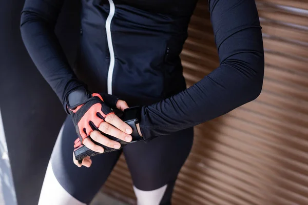 Cropped view of woman standing and touching sport gloves — Stock Photo