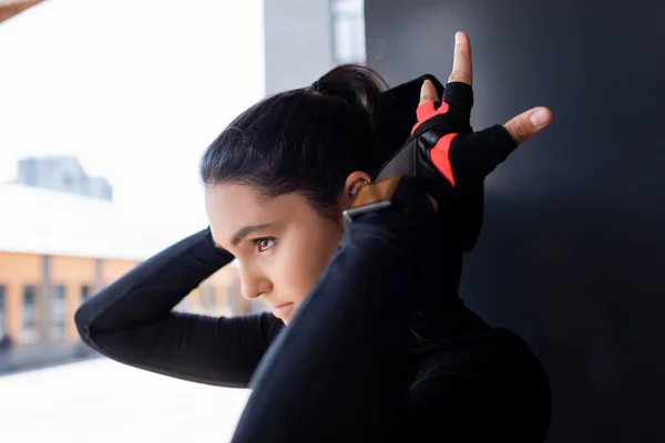 Selective focus of beautiful young sportswoman touching hood on hoodie — Stock Photo