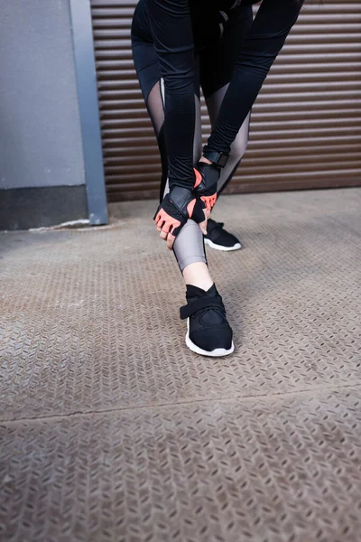 Cropped view of young sportswoman touching leggings — Stock Photo