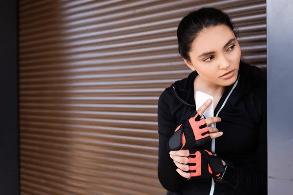 Молодая спортсменка держит в руках смартфон и отворачивается — стоковое фото