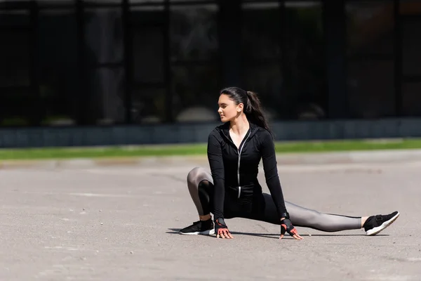 Sonnenlicht auf attraktiver junger Sportlerin, die sich auf Asphalt dehnt — Stockfoto