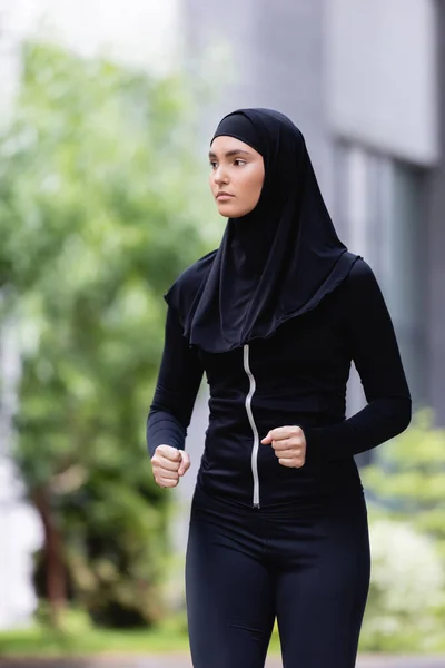 Young arabian sportswoman in hijab and sportswear jogging outside — Stock Photo