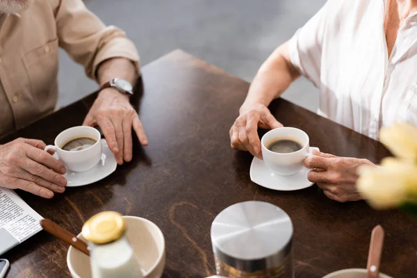 Vista recortada de pareja mayor tomando café durante el desayuno en casa - foto de stock