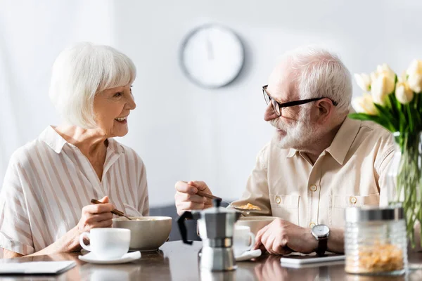 Selektiver Fokus einer lächelnden Frau, die ihren Mann beim Essen von Müsli in der Küche ansieht — Stockfoto