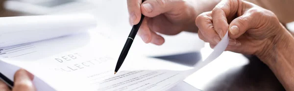 Panoramic crop of senior couple holding papers with debt collection lettering and pen — Stock Photo