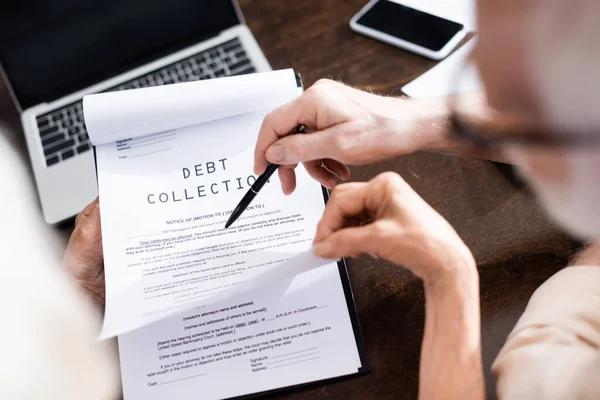 Selective focus of senior man holding pen near wife with debt collection lettering on papers — Stock Photo
