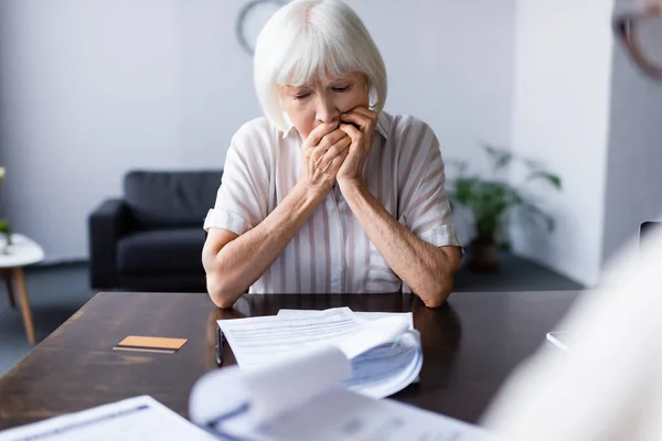 Focus selettivo della donna anziana sconvolta che guarda i documenti vicino alla carta di credito a casa — Foto stock