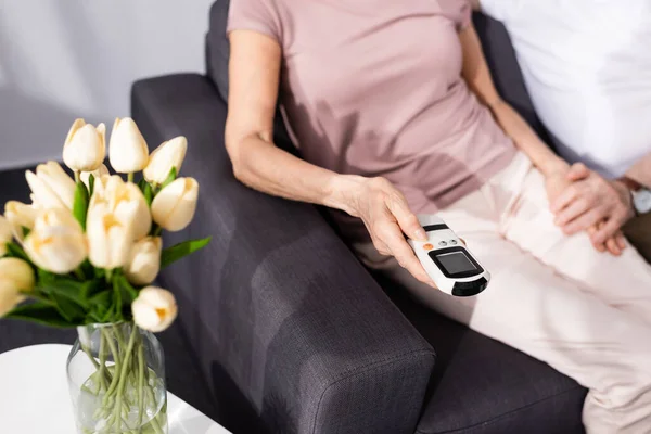 Vue recadrée de la femme âgée tenant télécommande du climatiseur près de l'homme à la maison — Photo de stock