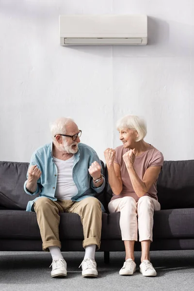 Lächelndes Senioren-Paar schaut einander an und zeigt Yah-Geste zu Hause — Stockfoto