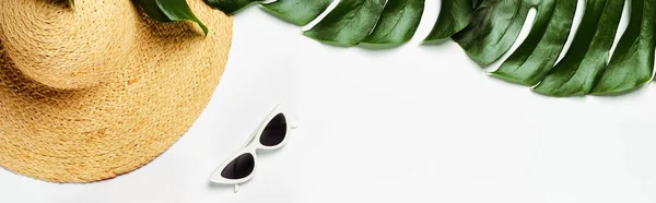 Vue de dessus des feuilles de palmier vert, chapeau de paille et lunettes de soleil sur fond blanc, vue panoramique — Photo de stock