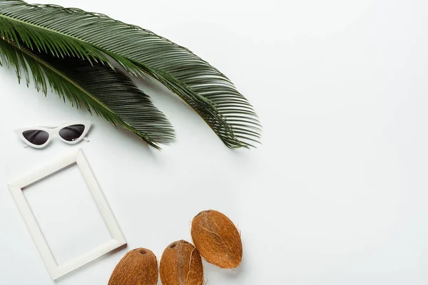 Top view of green palm leaves, sunglasses, coconuts and square frame on white background — Stock Photo